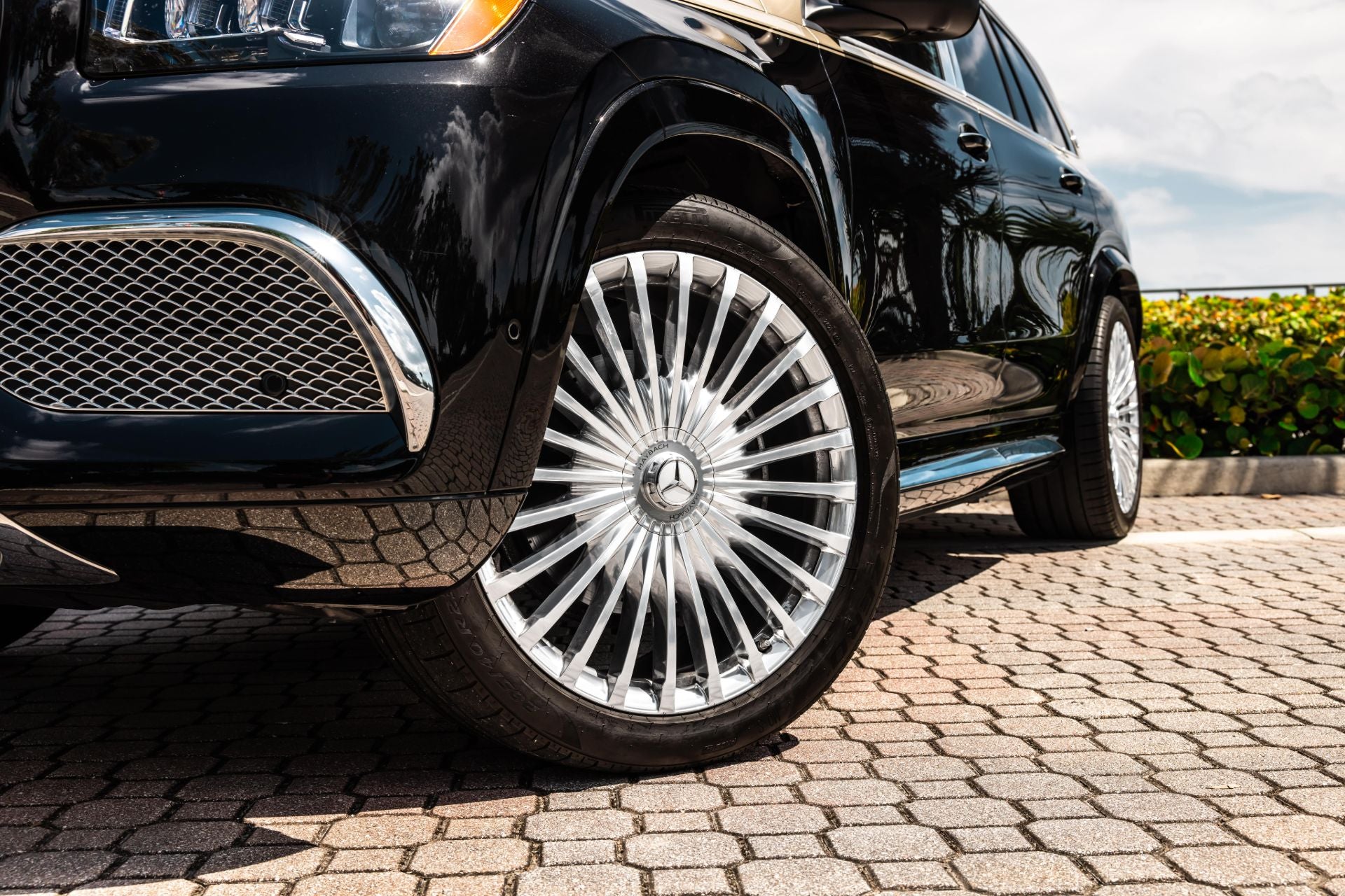 Close-up of a Mercedes Maybach GLS600 SUV's wheel with a visible Mercedes-Benz logo on a cobblestone street.