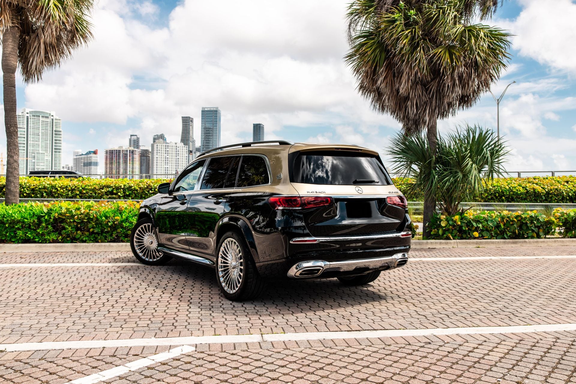 Mercedes Maybach GLS600 SUV parked on a paved road with palm trees and city skyline in the background