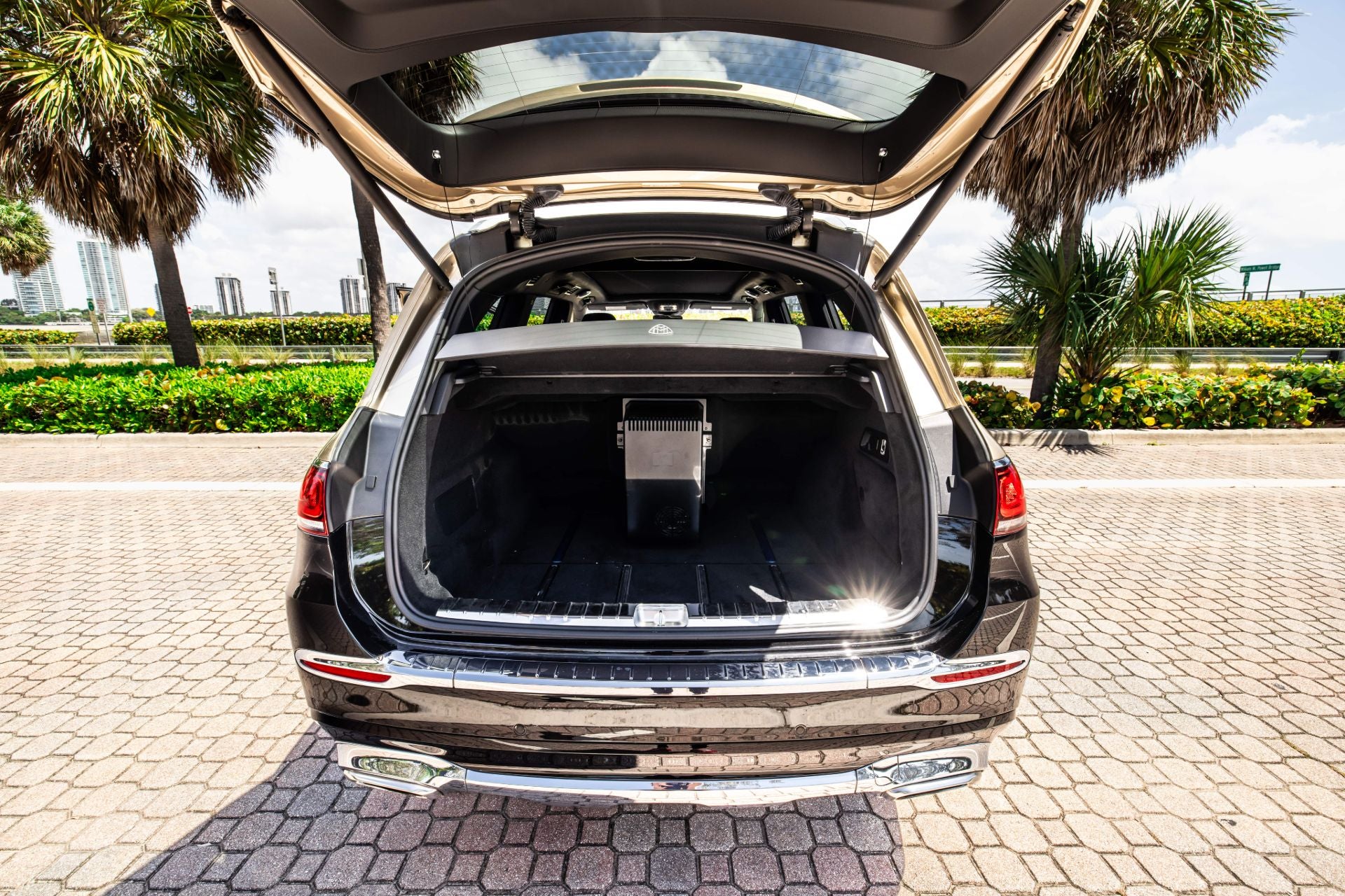 Mercedes Maybach GLS600 trunk open on a paved area with palm trees in the background