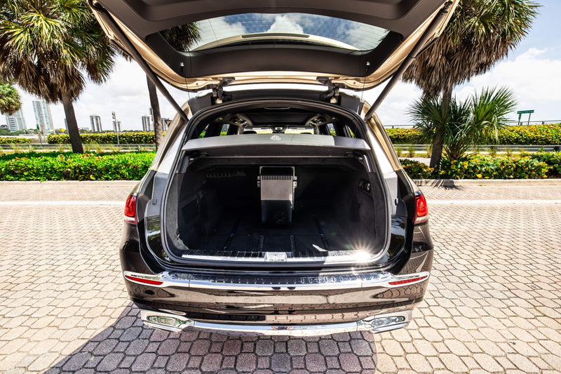Mercedes Maybach GLS600 trunk open on a paved area with palm trees in the background